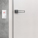 Open white door with metallic handle. The door to the bedroom