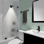 A small modern bathroom with a dark vanity, mirror frame, and ha